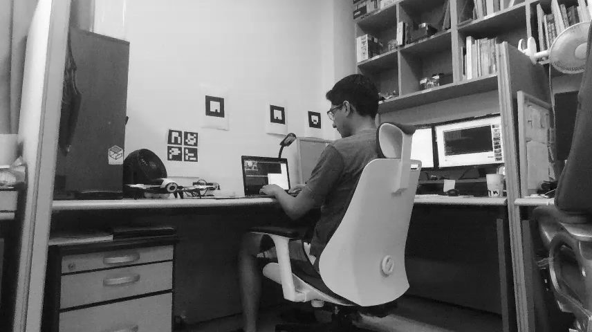 David working at his desk with multiple screens and a robot